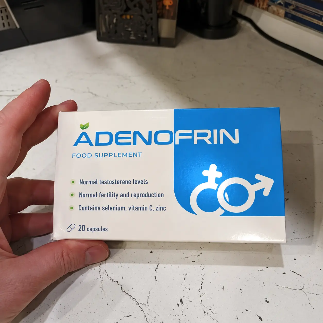Caja de Adenofrin sostenida con una mano en una foto real